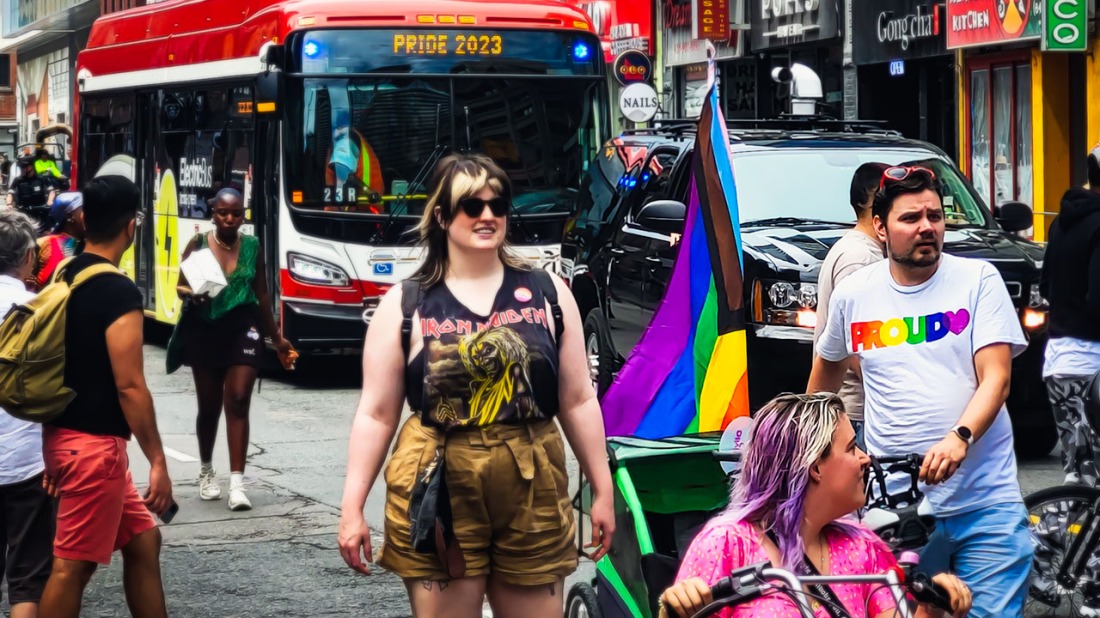 People walking down Yonge St. in front of TTC bus during 2023 Pride Toronto Festival